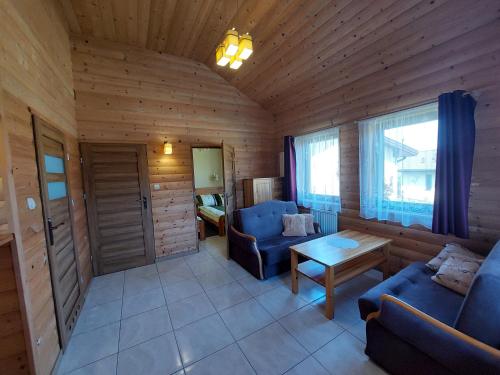 a living room with two blue chairs and a table at Domki Letniskowe Cyprys in Chańcza