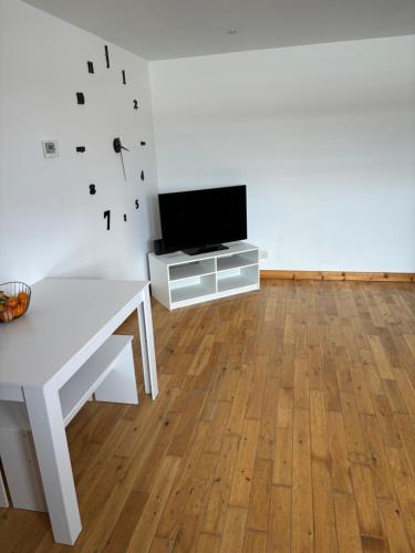 a living room with a white table and a tv at MacIver City Apartments Farraline Court in Inverness