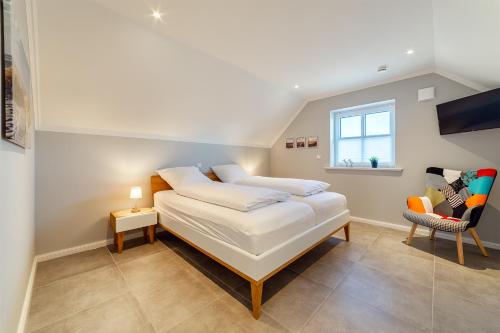 a bedroom with a bed and a window and a chair at Hus in Luv in Greetsiel