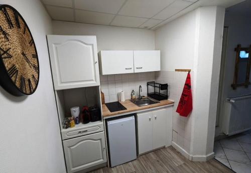 une petite cuisine avec des armoires blanches et un évier dans l'établissement Paisible - Proche Palais des Sports et Zénith, à Caen