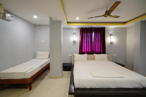 a bedroom with two beds and a ceiling fan at Hotel Sai Golden Rooms Deluxe in Tirupati