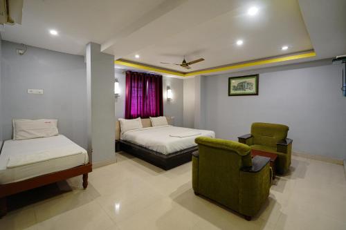 a hotel room with two beds and a chair at Hotel Sai Golden Rooms Deluxe in Tirupati