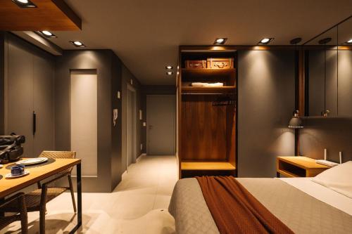 a bedroom with a bed and a desk and a table at Lindo Studio, Central, Com Garagem e Academia! in Pelotas