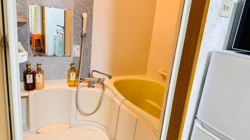 a bathroom with a yellow tub and a sink at ゲストハウス ROOASiS 常盤町 101 in Shichibanchō
