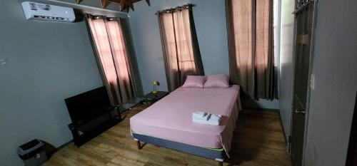 a small bedroom with a pink bed with pink sheets at JJ Guest House in Branns Hamlet