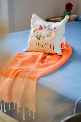 an orange and white pillow on top of a bed at Planeta Country House & Beach Club in Menfi