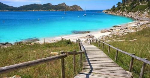 a wooden boardwalk leading to a beach with the ocean at Villa Papona 1 in Moaña