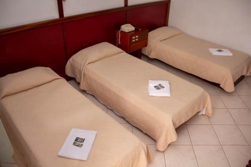 three beds in a room with towels on them at HOTEL DOMHOF in Blumenau