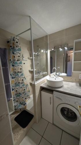 une salle de bain avec un lavabo et une machine à laver dans l'établissement Grand Appartement avec une Chambre et une Mezzanine - SAPHIR 20, à Canet