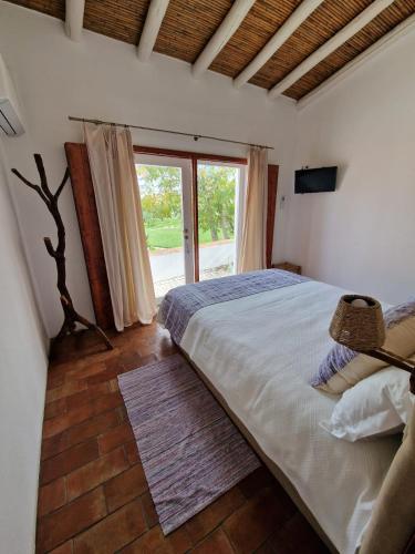 a bedroom with a large bed and a large window at Horta das Laranjas in Serpa