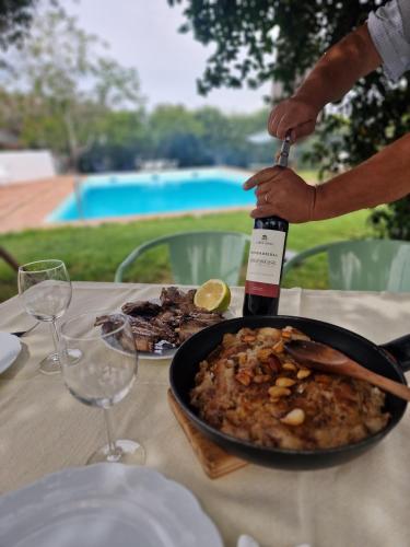 a person pouring a bottle of wine into a plate of food at Horta das Laranjas in Serpa