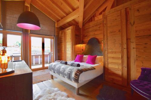 a bedroom with a bed with pink pillows at Chalet Valambrun - unashamedly luxurious Alpine living in Les Gets