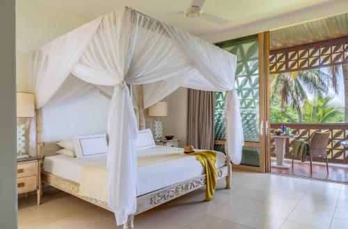 a bedroom with a canopy bed and a balcony at Melia Zanzibar in Kiwengwa