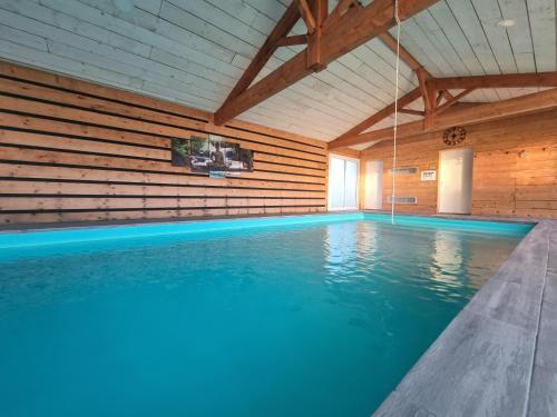 a swimming pool with blue water in a wooden building at Le Cocon de Lily in Saint-Savin-de-Blay
