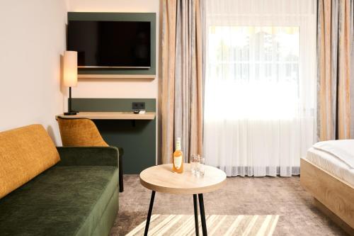 a hotel room with a couch and a bed and a table at Hotel SCHNEIDER in Allersberg