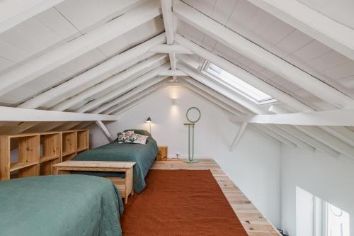 a attic bedroom with two beds and a window at Avenca da Praia - Tiny House 4 Beach & Surf Lisbon Getaway in Parede