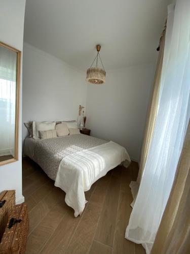 a white bedroom with a bed and a chandelier at Casa do Montinho in Caminha