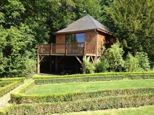 a wooden cabin with a deck in a garden at Cabane avec Jacuzzi privatif du Manoir du Parc - Adults only in Amboise