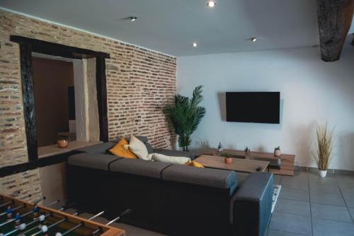 un salon avec un canapé et un mur de briques dans l'établissement Maison 6 personnes, Piscine privée, jardin, à Moulins