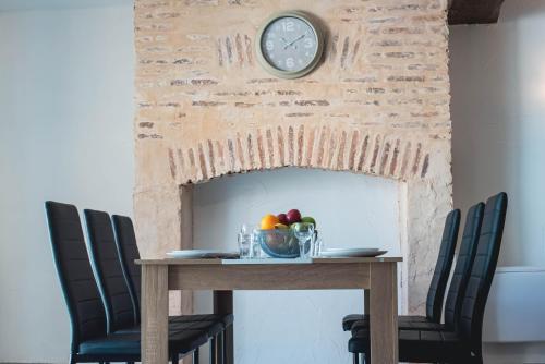 a table with a clock on a brick fireplace at Maison 6 personnes - terrasse et jardin in Moulins