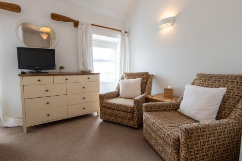 a living room with two chairs and a dresser with a television at Sea Breezes in Moelfre