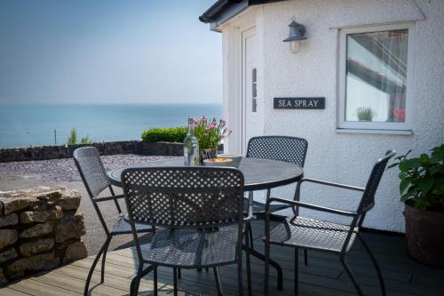 a table and chairs on a patio with the ocean at Sea Spray in Moelfre