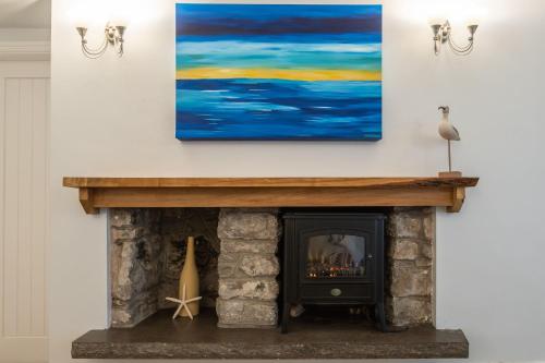 a living room with a fireplace and a painting on the wall at Sea Spray in Moelfre