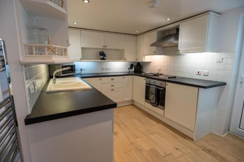 a kitchen with white cabinets and a black counter top at Sea Spray in Moelfre