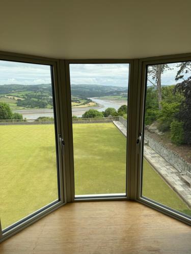 a room with three windows with a view of a field at The Manor Boutique Hotel Restaurant and Bar in Conwy