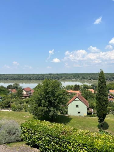 a small white house in a field with a lake at Queen of Danube in Aljmaš