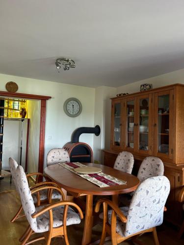 a dining room table with chairs and a clock on the wall at Queen of Danube in Aljmaš
