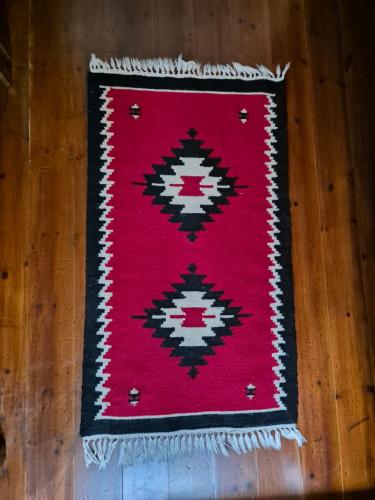 a red rug sitting on a wooden table at Timo's Guest House in Berat