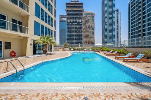 a large swimming pool with chairs and buildings at Luxury studio at JLT near metro in Dubai