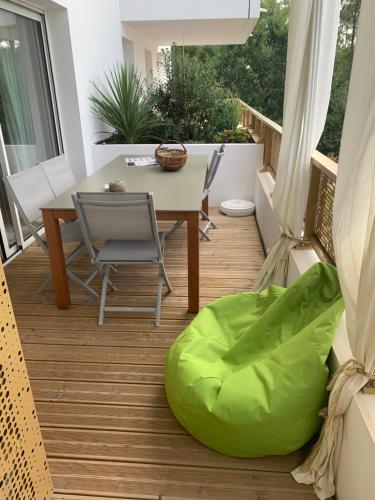 un balcon avec une table et un pouf vert dans l'établissement Appartement neuf au calme de Capbreton, à Capbreton