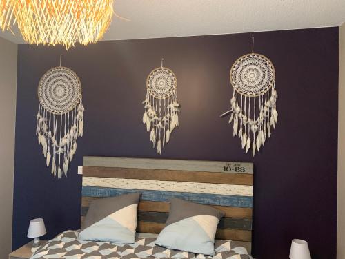 une chambre avec deux attrape-rêves suspendus au-dessus d'un lit dans l'établissement Appartement neuf au calme de Capbreton, à Capbreton