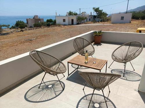 a patio with three chairs and a table on a roof at Sea view Pine house in Makry Gialos