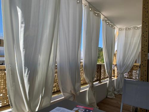 d'un balcon avec des rideaux blancs et une fenêtre. dans l'établissement Appartement neuf au calme de Capbreton, à Capbreton