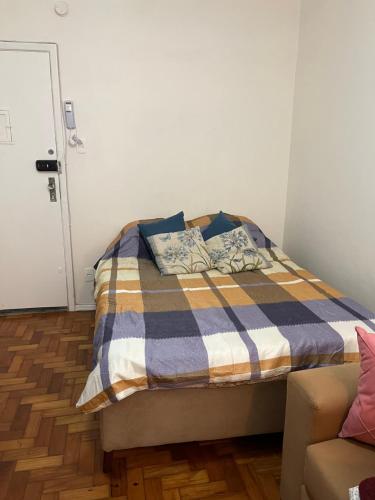 een slaapkamer met een bed met een geruite deken bij Lindo Studio Flamengo in Rio de Janeiro