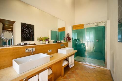 a bathroom with two sinks and a glass shower at Castello Di Postignano Relais in Sellano