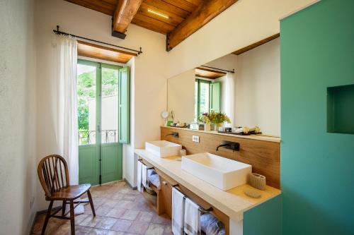 a bathroom with two sinks and a window at Castello Di Postignano Relais in Sellano
