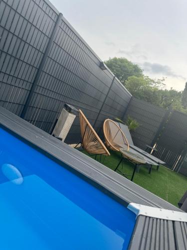 two chairs and a table on the side of a swimming pool at Reve D Amazonie & Spa in Les Mages