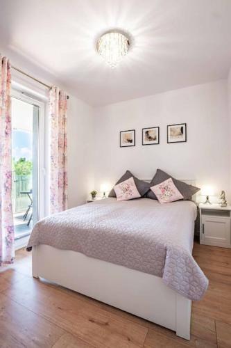 a white bedroom with a bed and a window at Blue Sun Apartament Słoneczny in Kołobrzeg
