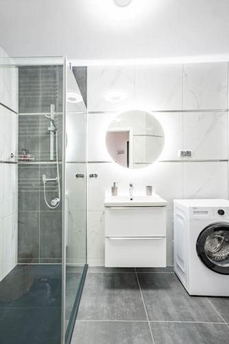 a white bathroom with a sink and a washing machine at Blue Sun Apartament Słoneczny in Kołobrzeg