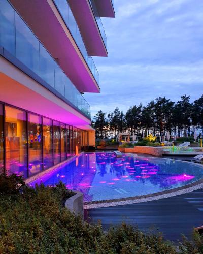 a swimming pool in front of a building with purple lights at WAVEVIEW PREMIUM 10th Floor Baltic View in Międzyzdroje