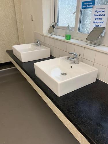 a bathroom with two white sinks and a mirror at Sleeping Giant outdoor adventure flat in Pen-y-cae