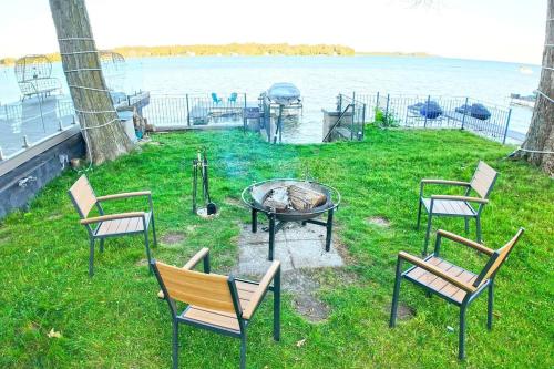 a group of chairs and a fire pit next to the water at Charming Cottage on Lake Simcoe in Orillia