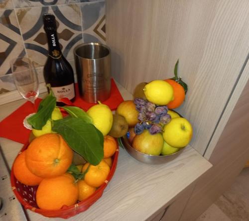 two bowls of fruit on a shelf with a bottle of wine at Antico Vicolo - Appartamento Rebecca in Vercelli