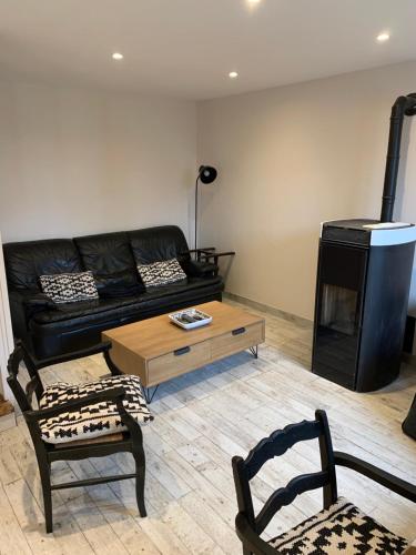 - un salon avec un canapé noir et une table basse dans l'établissement Le logis - Lampaul-Guimiliau, à Lampaul-Guimiliau