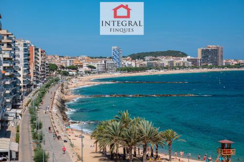 a view of a beach with palm trees and the ocean at Apartament Made in Costa Brava in Sant Antoni de Calonge