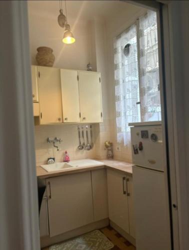 une cuisine avec des armoires blanches, un évier et un réfrigérateur dans l'établissement Little garden, à Nice